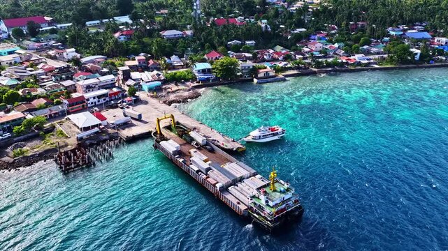 Beautiful wide drone shot over Padre Burgos in Southern Leyte, Philippines. Features a long river canal and thick mangrove forest running alongside a colorful coastal town and ocean harbor port.