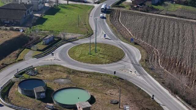 Roundabout connecting SP4 Bardi and SP21 Val d'Arda near Lugagnano Val d'Arda, Province of Piacenza, Emilia-Romagna, Italy, surrounded by agricultural land and rural road infrastructure, aerial obliqu