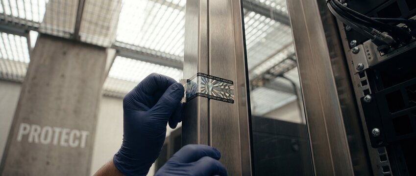Security seal sticker applied to server rack cabinet doors for physical data protection and compliance audits, preventing unauthorized hardware access at a secure server center and cloud hosting hubs.