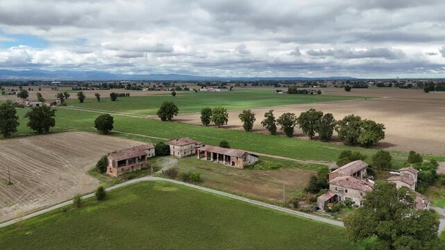 Po Valley farmland near the Trebbia and Po River junction in Province of Piacenza, Emilia-Romagna, Italy, with cereal crops, rural farmhouses and Northern Apennine foothills, aerial forward flyover.