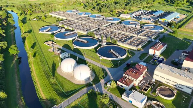 Aerial view of water treatment facility showcasing circular tanks and machinery. Sewerage system surrounded by greenery. Modern industrial plant of big city. Ecology friendly factory