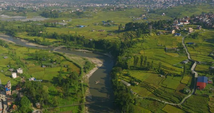 Drone glides forward over the winding Bagmati River, capturing the lush green terrace farmlands and countryside landscape of Pharping Nepal