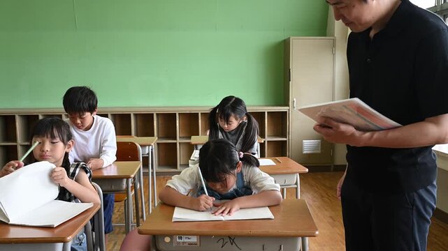 教室で勉強する女子小学生を傍で見守る男性教師	