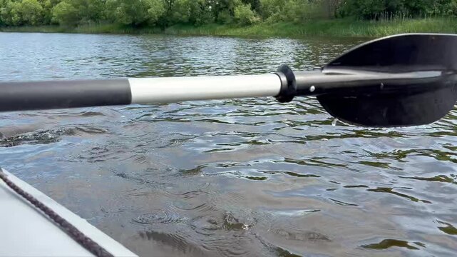 video captures the rhythmic action of paddling a boat on a calm river. Unity with nature