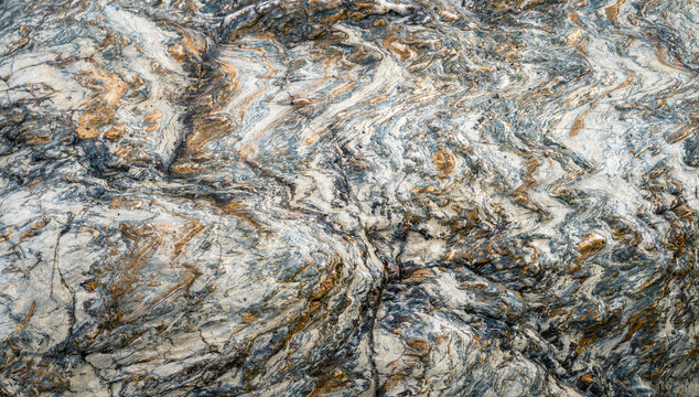 Wavy striations in a quartzitic rock interspersed with golden veins of pyrite