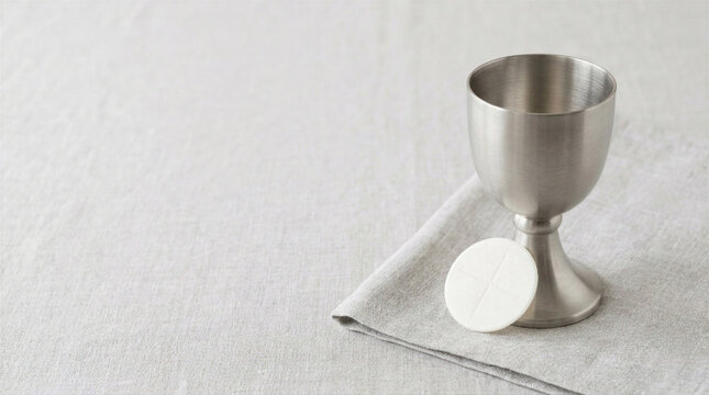 Silver chalice and host on linen cloth. Catholic holy communion concept. Eucharistic wafer and cup symbols of Jesus Christ sacrifice. Christian religious celebration and prayer time.