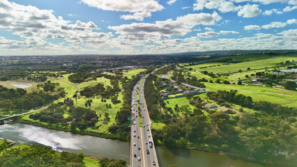 Obraz premium Noarlunga Downs, South Australia – 4K aerial drone footage of river crossing, M2 highway bridge, green parklands, wetlands, suburban homes, open countryside and scenic urban landscapes