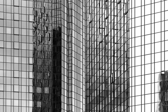 Monochrome glass facade reflection builds a grid pattern across tower architecture, turning urban business forms into layered texture
