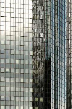 Glass facade reflection covers a vertical tower surface, where architecture, grid, windows and business forms repeat in tight alignment