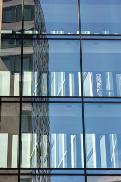 Blue glass facade windows reveal reflection, architecture, office interior lines and business grid structure across stacked floors