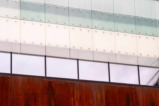 Glass and metal panels divide a facade, where architecture, building windows, business texture and contrast meet across layered surfaces