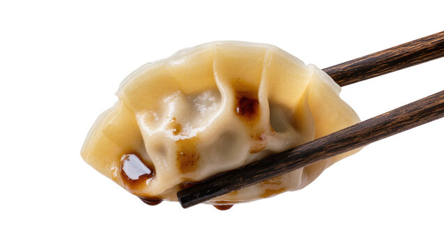 Steaming hot dumpling held by chopsticks, drizzled with soy sauce