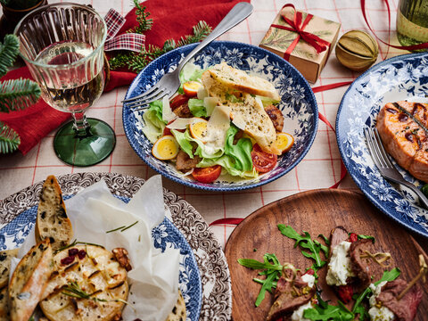 Festive table setting with assorted dishes including salad, grilled meat, and crusty bread for holiday gatherings