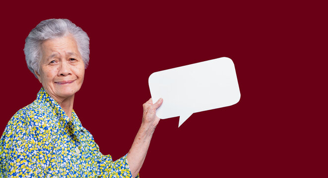 Senior Woman Holding Blank Speech Bubble Against Red Background