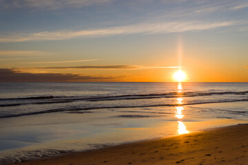 Obraz premium Golden sunset reflecting on calm beach, Algarve coast, Portugal