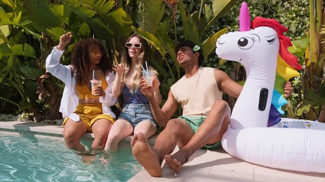 Diverse friends dancing and drinking cocktails at a summer pool party