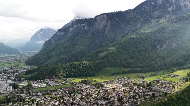 Picturesque alpine mountain village Switzerland valley Glarus canton base of Swiss Alps, aerial