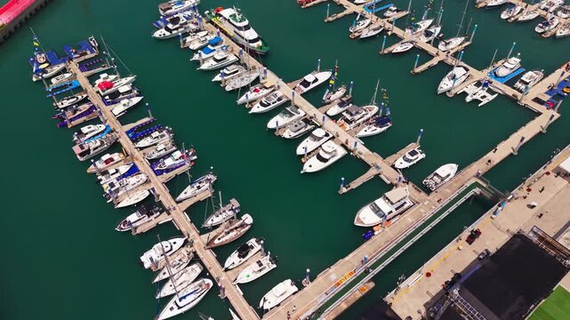 Aerial top-down flyover above Jeongok Marina with rows of moored yachts and boats on floating docks during Hwaseong Boating Festival in South Korea