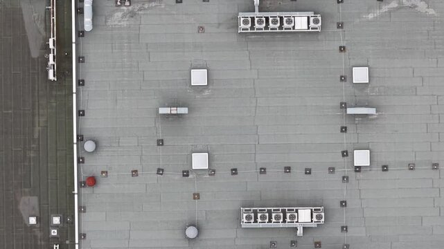 Aerial perspective of a building's rooftop showcasing various HVAC units and mechanical equipment against a gray surface.