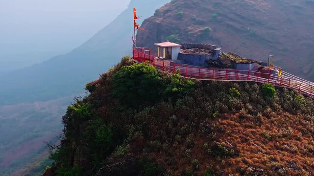 Hill top Deviramma Temple with religion flag and safety railings at Baba Budangiri, Chikkamagaluru, Karnataka, India. day time, semi orbit shot, drone shot, 4k.