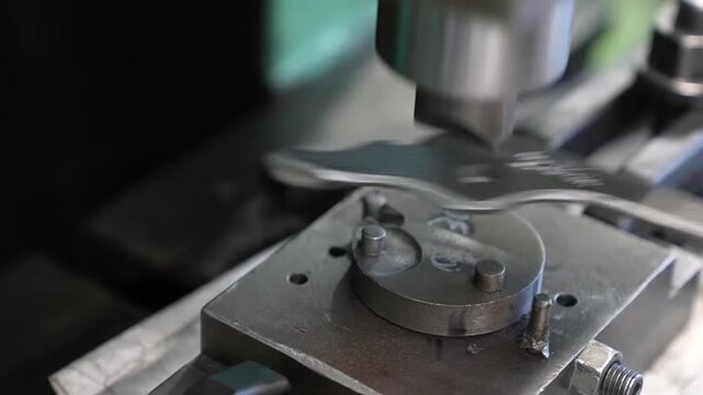 Extreme close-up of forged steel pliers held in precision assembly jig with pivot rivet