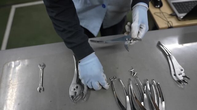 Quality inspector examining assembled pliers and wrenches at inspection workstation in factory