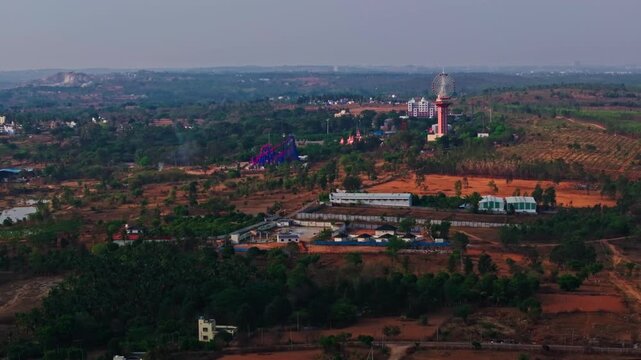 Wide shot of Wonderla Amusement Park with resort, haze, sky and crop field lands at Bannikuppe, Bidadi, Bangalore, karnataka, india. day time, push in shot, drone shot, 4k.