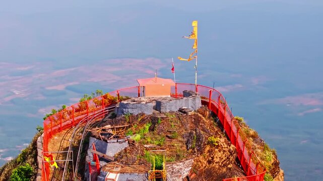 Hill top temple with flag, farming land, haze and Chandra Drona hill ranges at Nagenahalli, Baba Budangiri, chikkamagaluru, karnataka, india. day time, trucking shot, drone shot, 4k.