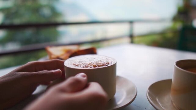 Closeup shot of girl hand holding coffee cup in outdoor cafe at Naggar, Himachal Pradesh, India. Morning coffee in mountains.