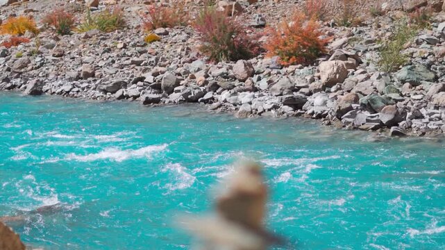 Beautiful blue river flowing in the Himalayas. Defocused stone tower near flowing Zanskar River in Ladakh, India. River seen from Phugtal monastery. Nature, environment and climate change concept.