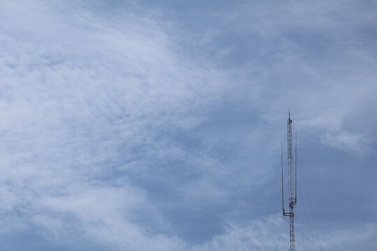 Radio transmitter tower broadcasting communication signals beneath clear blue sky.