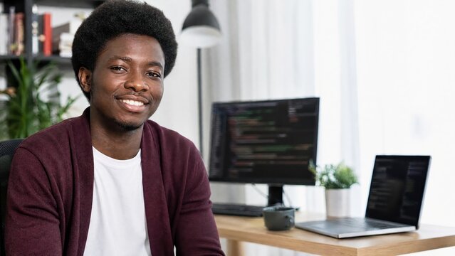 Generative AI, Smiling young Black male developer at home office desk with coding monitors