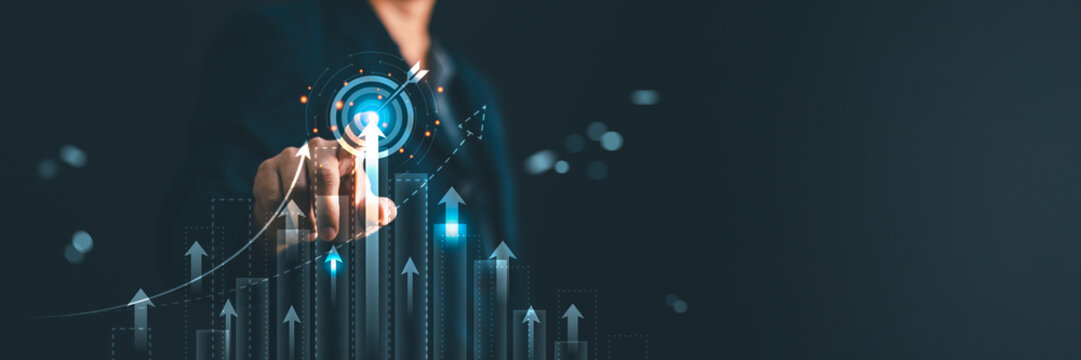 Businessman pointing at growing virtual bar chart graph and hologram target. Business strategy development, planning, financial analysis, corporate success and goals achievement concept