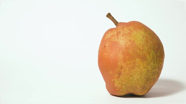 Single ripe pear fruit (Pyrus communis) isolated on white background, studio shot, video recorded in 60fps and 4K quality