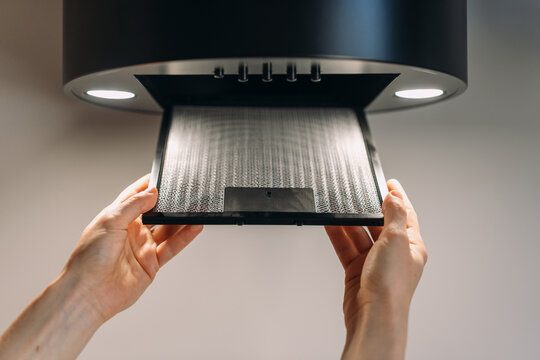 Woman removing filter on kitchen hood extractor