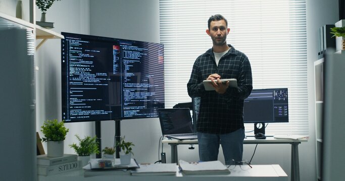 Lead Developer Delivering Presentation. Caucasian engineer explains program logic and AI integration to colleagues, demoing interfaces, databases and automation strategies for product innovation.