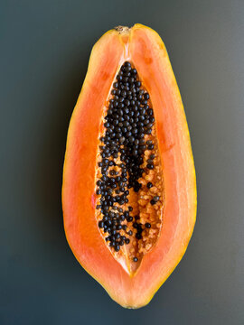 Half a papaya on a gray background. Close-up. Top view.