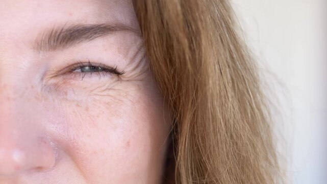 Woman touches and checks crow feet fine line wrinkles around eye area in anti-aging beauty concern closeup. Expression wrinkle footage for aesthetic clinic promotion, botox content, anti-wrinkle serum