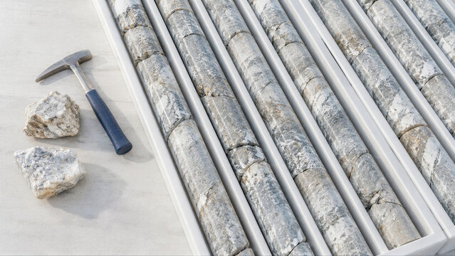 Geological core samples of rock in a tray with a geologist hammer for mineral research. Exploration of marble deposits and mining industry material analysis for geological survey.