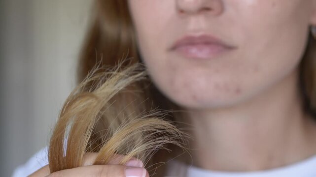 Woman holding dry hair strands while inspecting split ends at home. Minimal clean beauty concept for natural haircare brands, organic cosmetics and sulfate free restorative products.