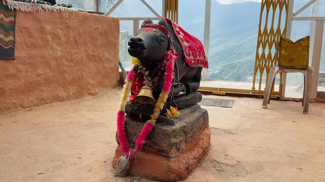 Sacred Nandi bull statue adorned with cloth and garlands in a Hindu temple courtyard.