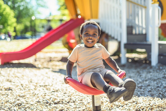 Happy young american child on playground swing this summer season