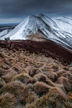 Point de vue sur les sommets de montagnes enneig&eacute;es du puy de la tache avec en premier plan des mottes d'herbes marron//France, Massif Central (63), Auvergne, Puy de Dome