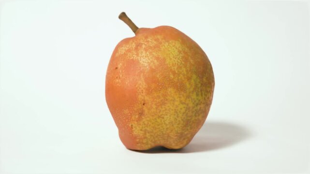 Single ripe pear fruit (Pyrus communis) isolated on white background, studio shot with right to left pan camera movement, video recorded in 60fps and 4K quality