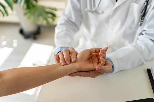 Close-up of physician checking patient&rsquo;s wrist during clinical examination in modern clinic. Healthcare assessment, diagnosis, patient care and professional medical practice