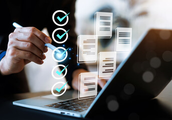 Professional businessman using a laptop with digital checklist and document icons. This conceptual image represents task management, quality assurance, workflow automation, paperless office. © wasan