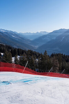 Type A safety structure with red protection net and OB pole at racecourse of the Alpine Ski World Cup in Crans-Montana, Switzerland with senic view over Rhone Valley