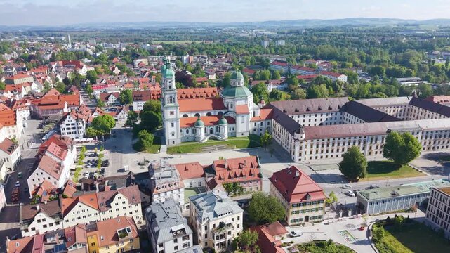 Orbiting aerial shot of Basilica Saint Lorenz Church in Kempten Allg&auml;u, Germany, featuring historic architecture, red rooftops, and the surrounding town square in Bavaria. UHD.
