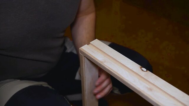 Craftsman in a carpentry workshop hammers nails with a pneumatic hammer. Making a wooden box. A close-up pneumatic nail gun putting nails in boards.