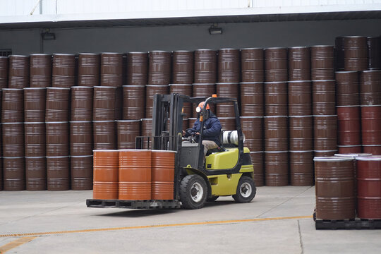 Montacargas transportando tambores met&aacute;licos en dep&oacute;sito industrial